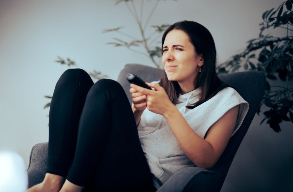 Woman squinting at TV screen, showing signs of needing glasses