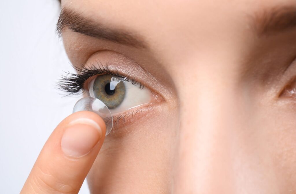 A person gently removes a contact lens from their eye at the end of a long day.