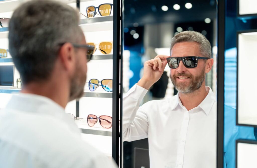 A person trying on sunglasses in front of a mirror inside an eyewear store.