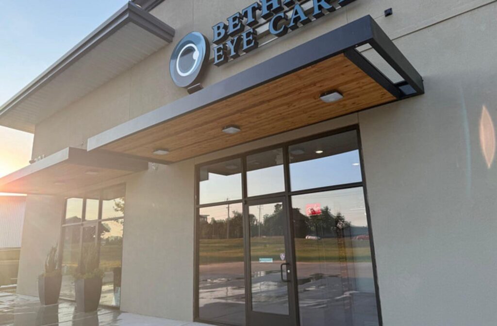 Exterior view of Bethany Eye Care, featuring the clinic’s sign above the glass entrance, a modern storefront, and a wood-paneled awning.